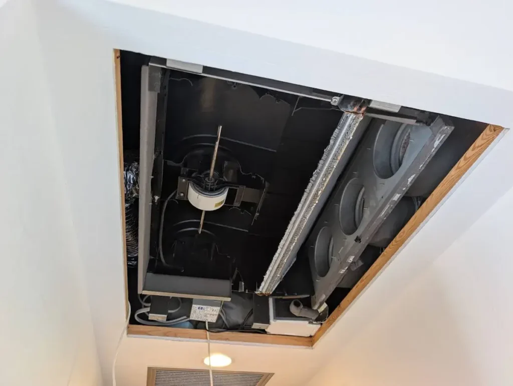 天井埋め込み型エアコンの内部ユニットが露出し、ファンやダクトが見える状態の写真。