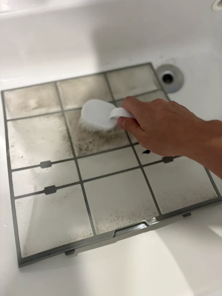 エアコンフィルターの汚れをブラシでこすり洗いしている様子