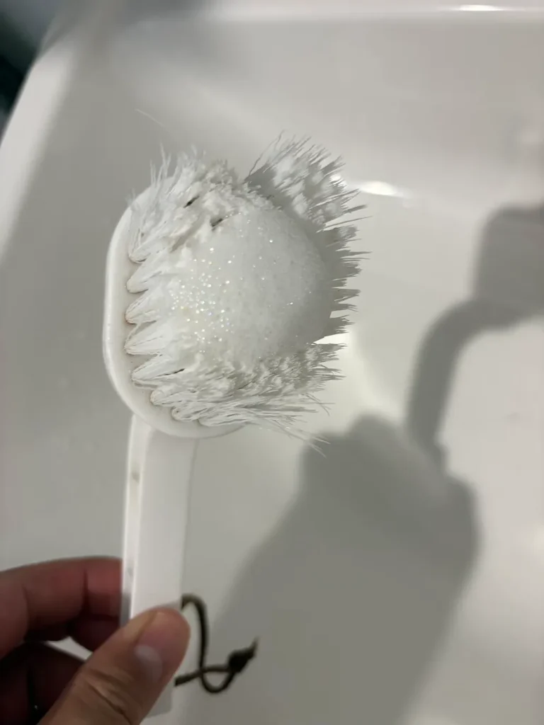 エアコンフィルターを洗うために泡をつけたブラシ