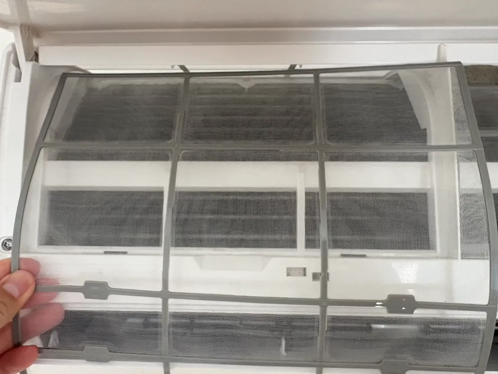 掃除して乾燥させたエアコンフィルターを本体に戻す様子