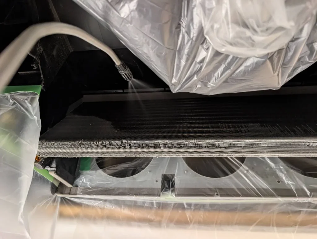 養生したZ空調の熱交換器を高圧洗浄しているクリーニング作業